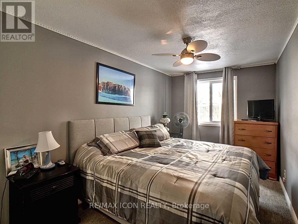 A bedroom with a bed, nightstand, and a ceiling fan.