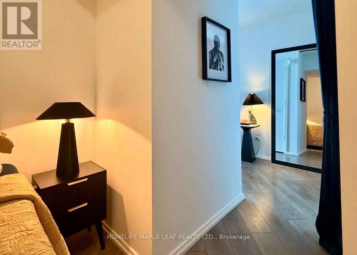 A bedroom with a bed, a lamp, and a picture on the wall.