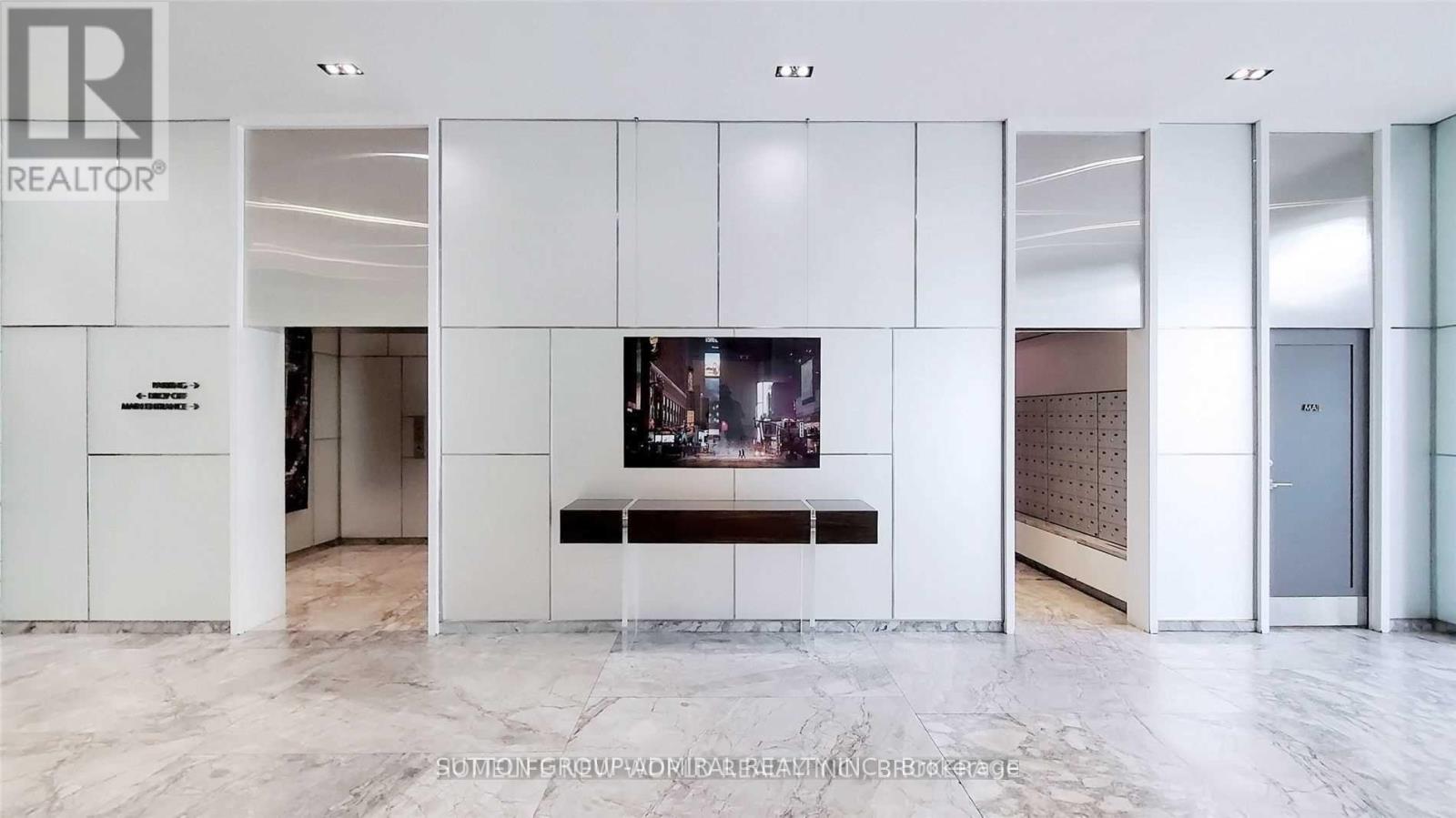 A white reception area with a TV and a bench.