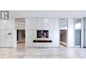 A white reception area with a TV and a bench.