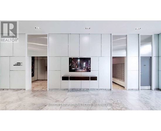 A white reception area with a TV and a bench.