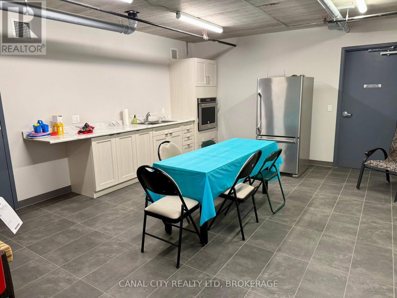A kitchen area with a table covered in a blue tablecloth and chairs around it.