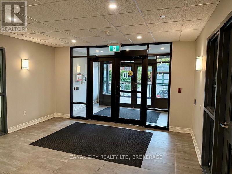 The image shows a foyer with a black mat on the floor and a glass door leading outside.