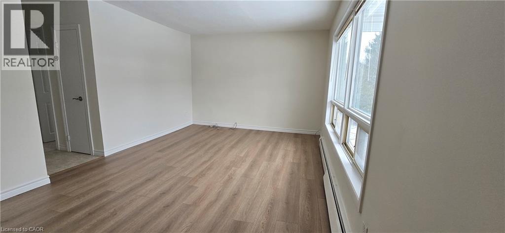 A room with wooden flooring and a window on the right side.