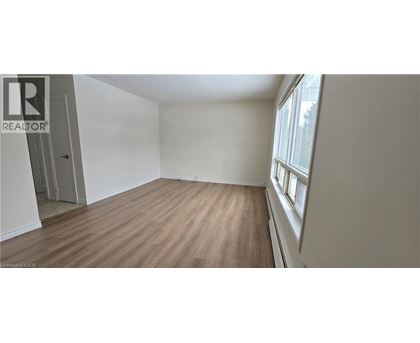 A room with wooden flooring and a window on the right side.