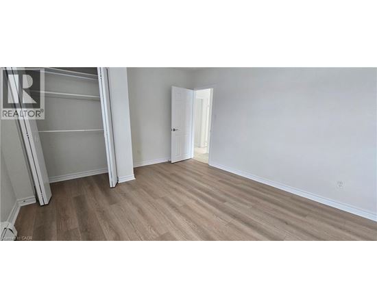 A bedroom with a white door and a wooden floor.