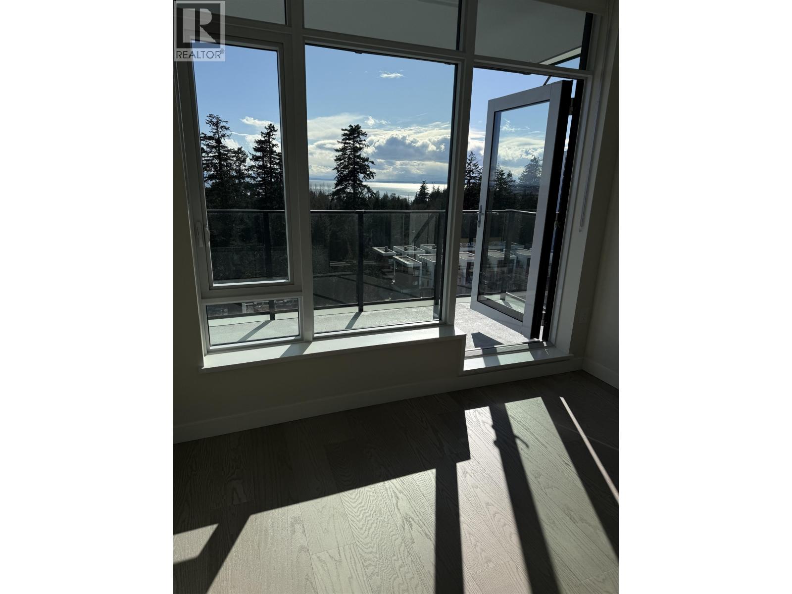 A window with a view of trees and a cloudy sky.