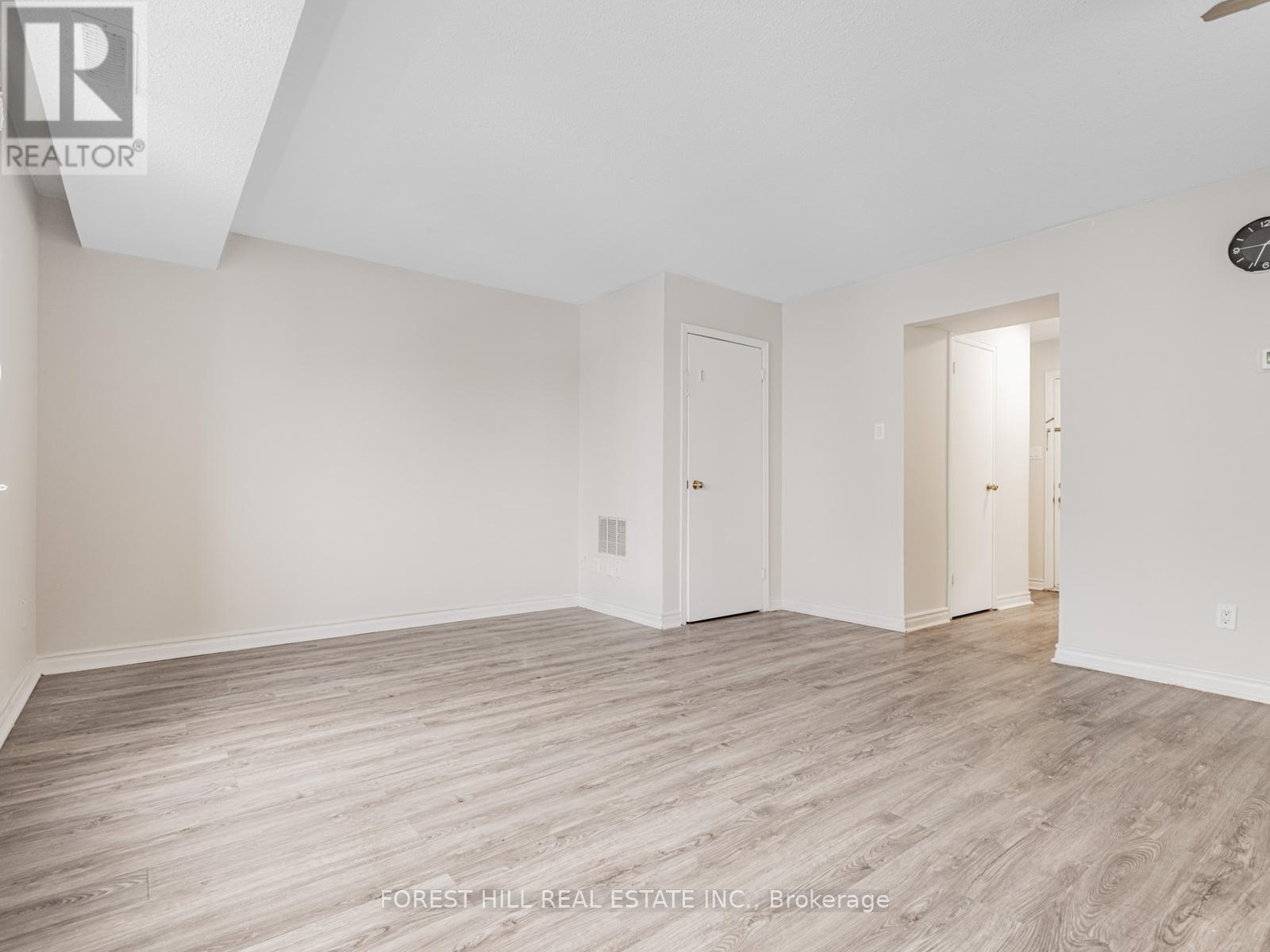 A spacious room with wood flooring and white walls.