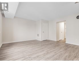 A spacious room with wood flooring and white walls.