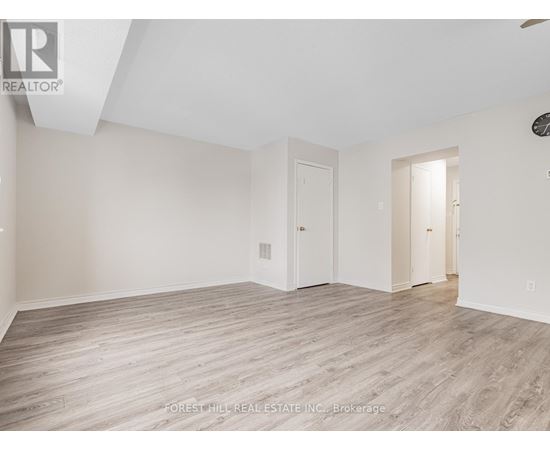 A spacious room with wood flooring and white walls.