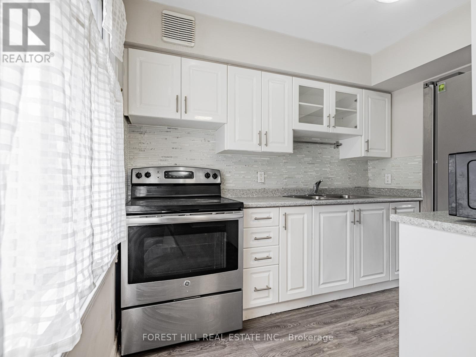 A kitchen with a stove top oven and white cabinets.
