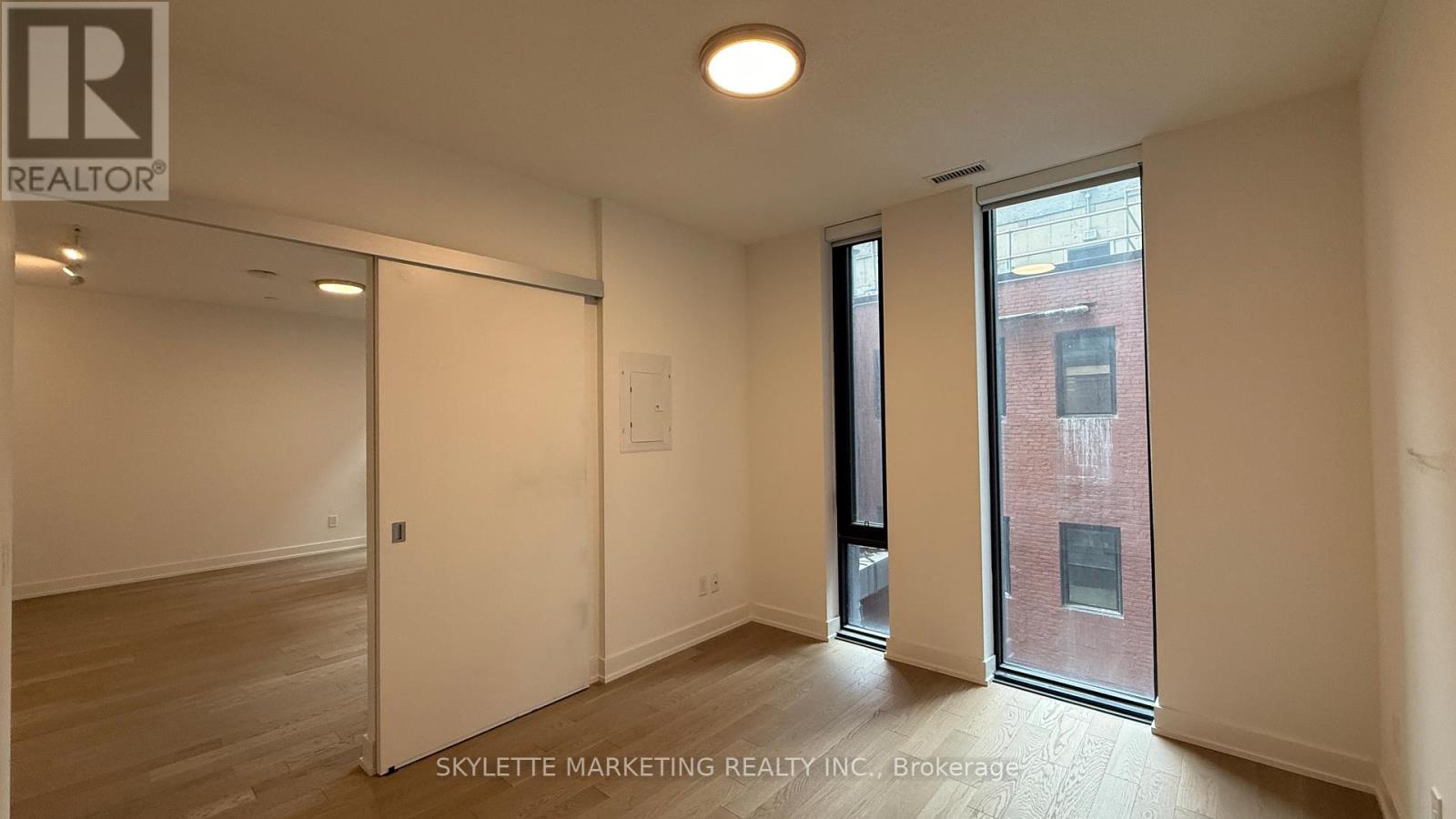 A room with a door and a window with a view of a building outside.