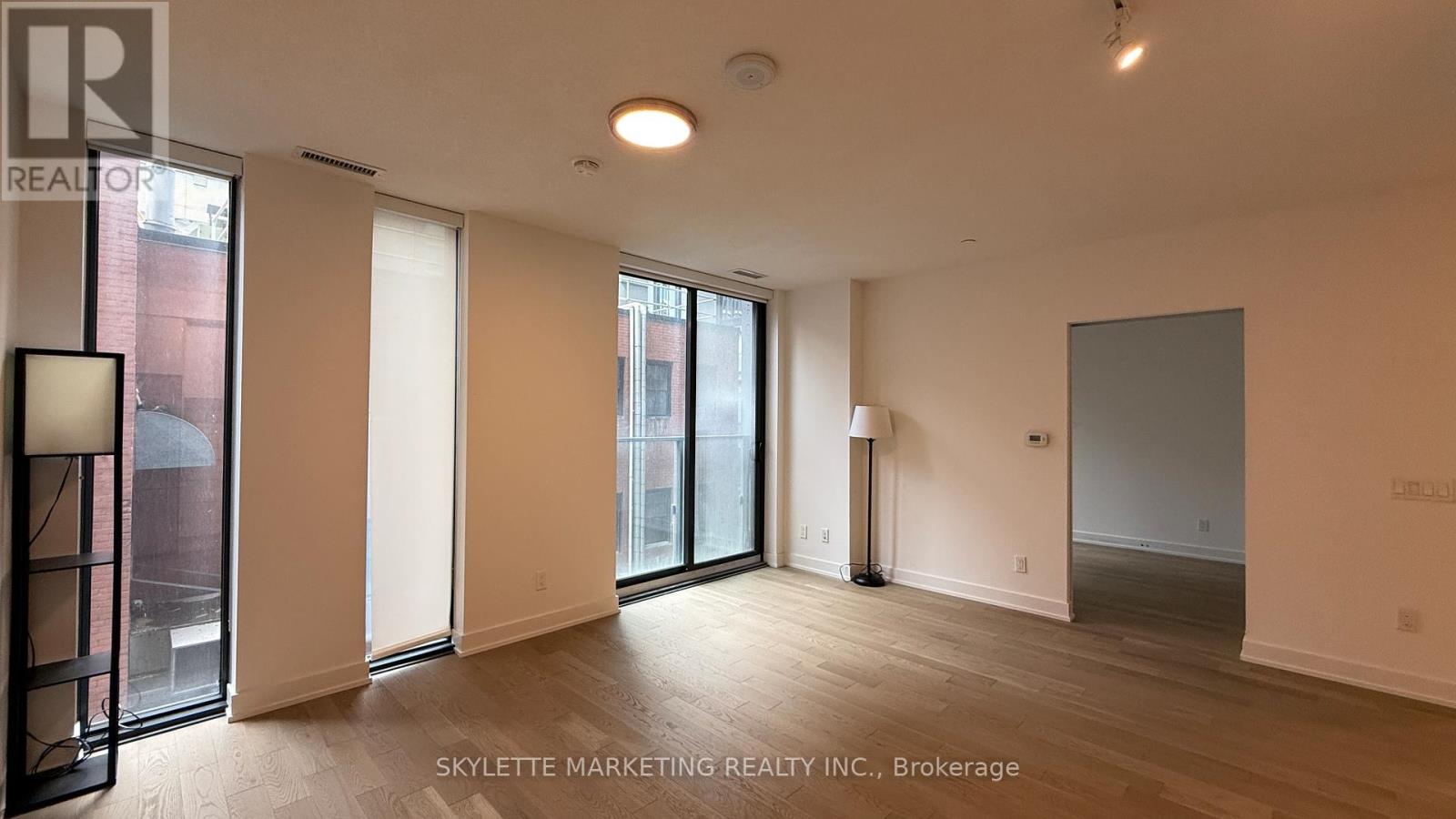 A spacious room with a large window and a lamp on the floor.