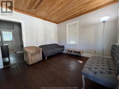 A living room with a grey couch and a wooden ceiling.