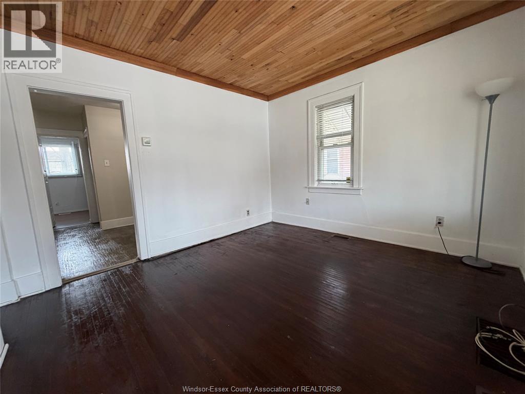 A room with wooden flooring and white blinds on the windows.