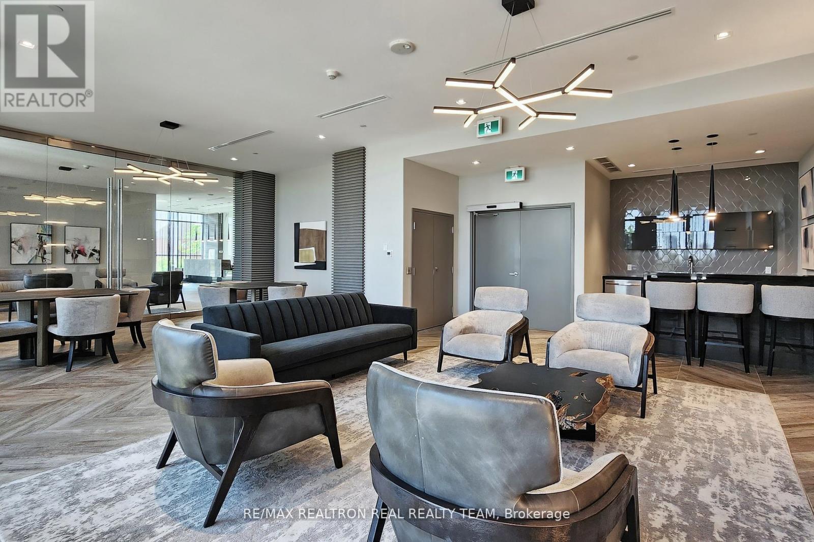 A modern living room with a black sofa and grey armchairs.