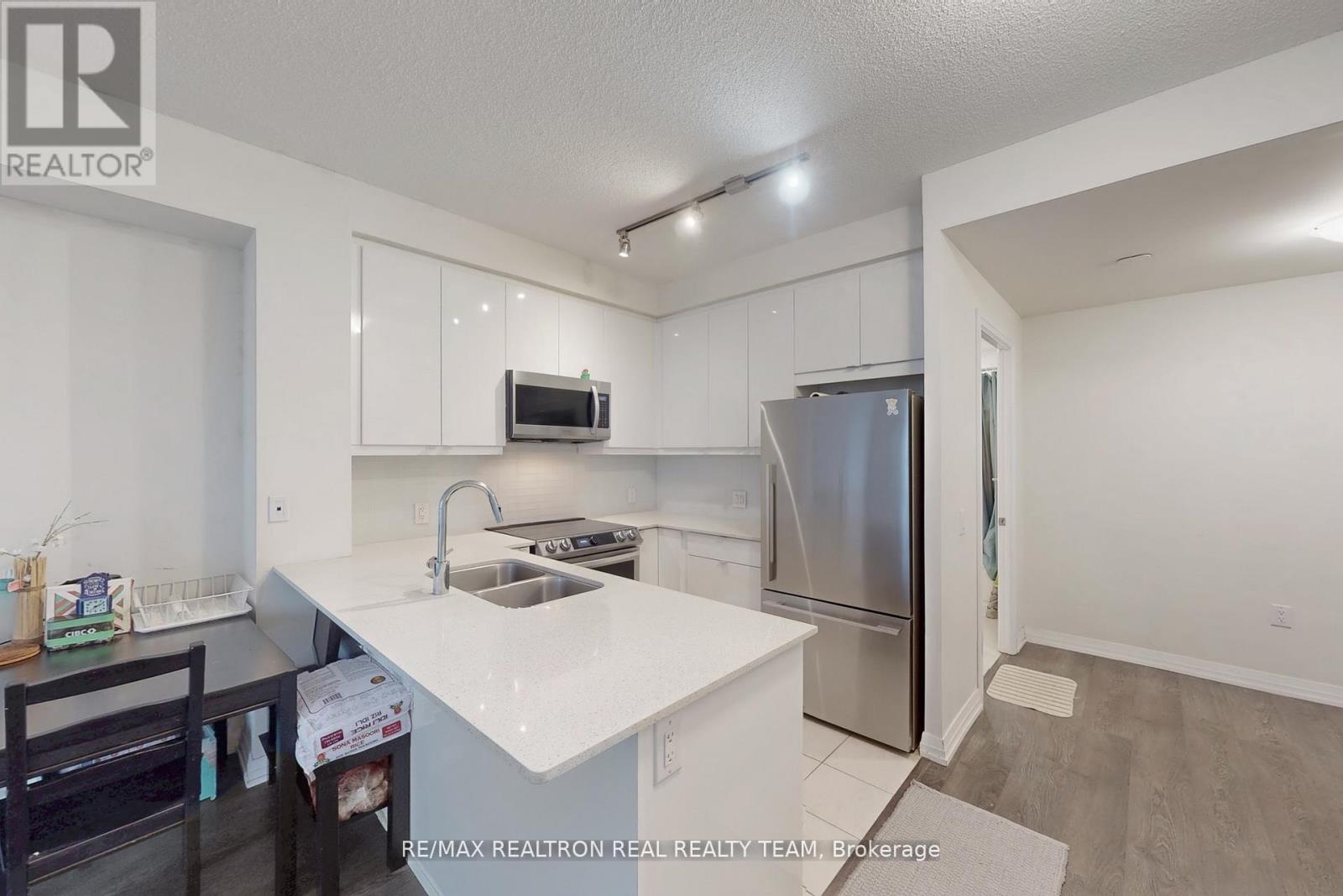 A kitchen with white cabinets and a stainless steel refrigerator.