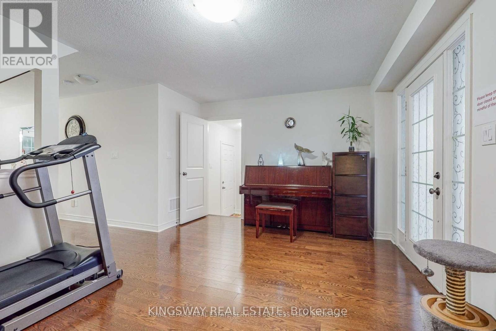 A room with a treadmill, a desk, and a chair.