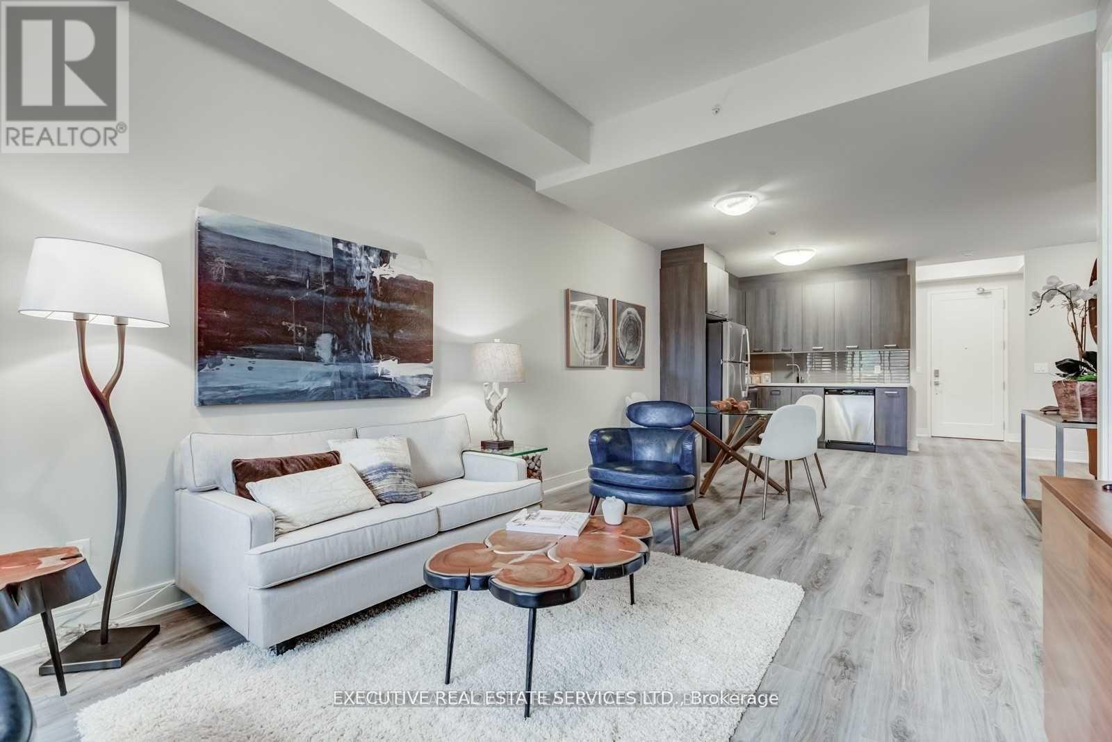 A living room with a white couch and a painting on the wall.