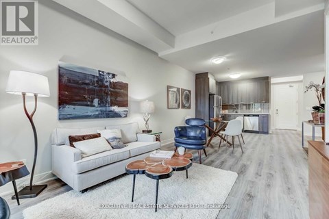 A living room with a white couch and a painting on the wall.