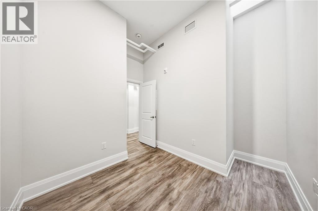 A spacious room with wood flooring and white walls.
