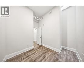 A spacious room with wood flooring and white walls.