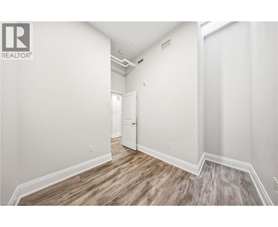 A spacious room with wood flooring and white walls.