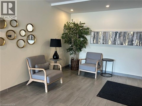A living room with two chairs, a table with a lamp, and a wall with circular mirrors.