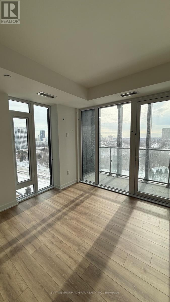 A room with wooden floors and large windows overlooking a cityscape.