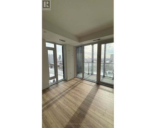 A room with wooden floors and large windows overlooking a cityscape.