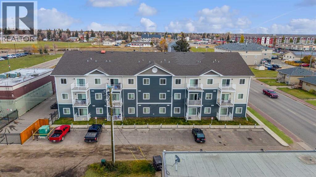 A large apartment complex with multiple buildings and cars parked in the driveway.