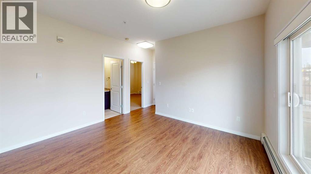 A room with wooden floors and white walls, with a doorway leading to another room.