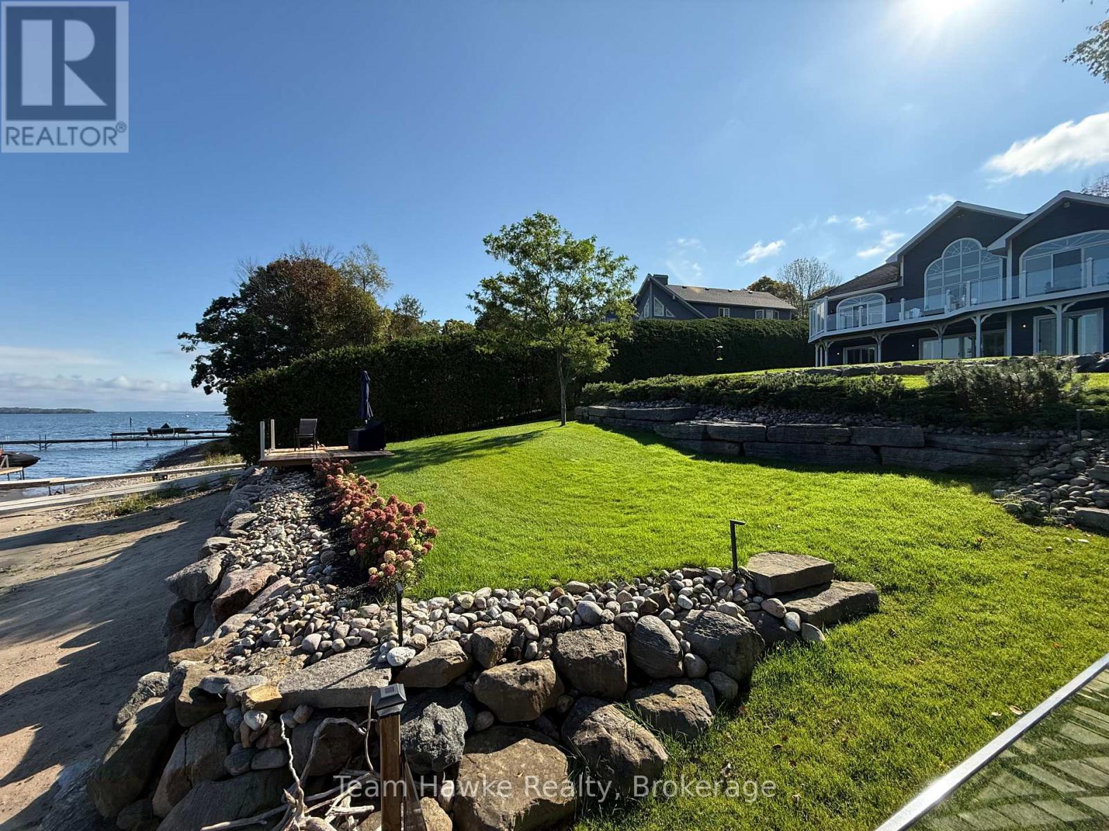 A stone wall separates a grassy area from a paved walkway.
