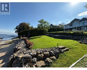 A stone wall separates a grassy area from a paved walkway.