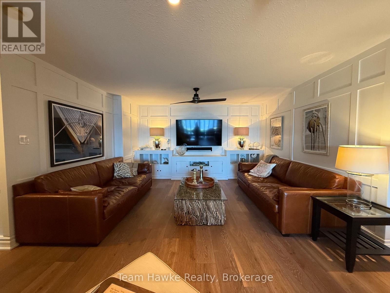 A living room with brown leather couches and a wooden floor.
