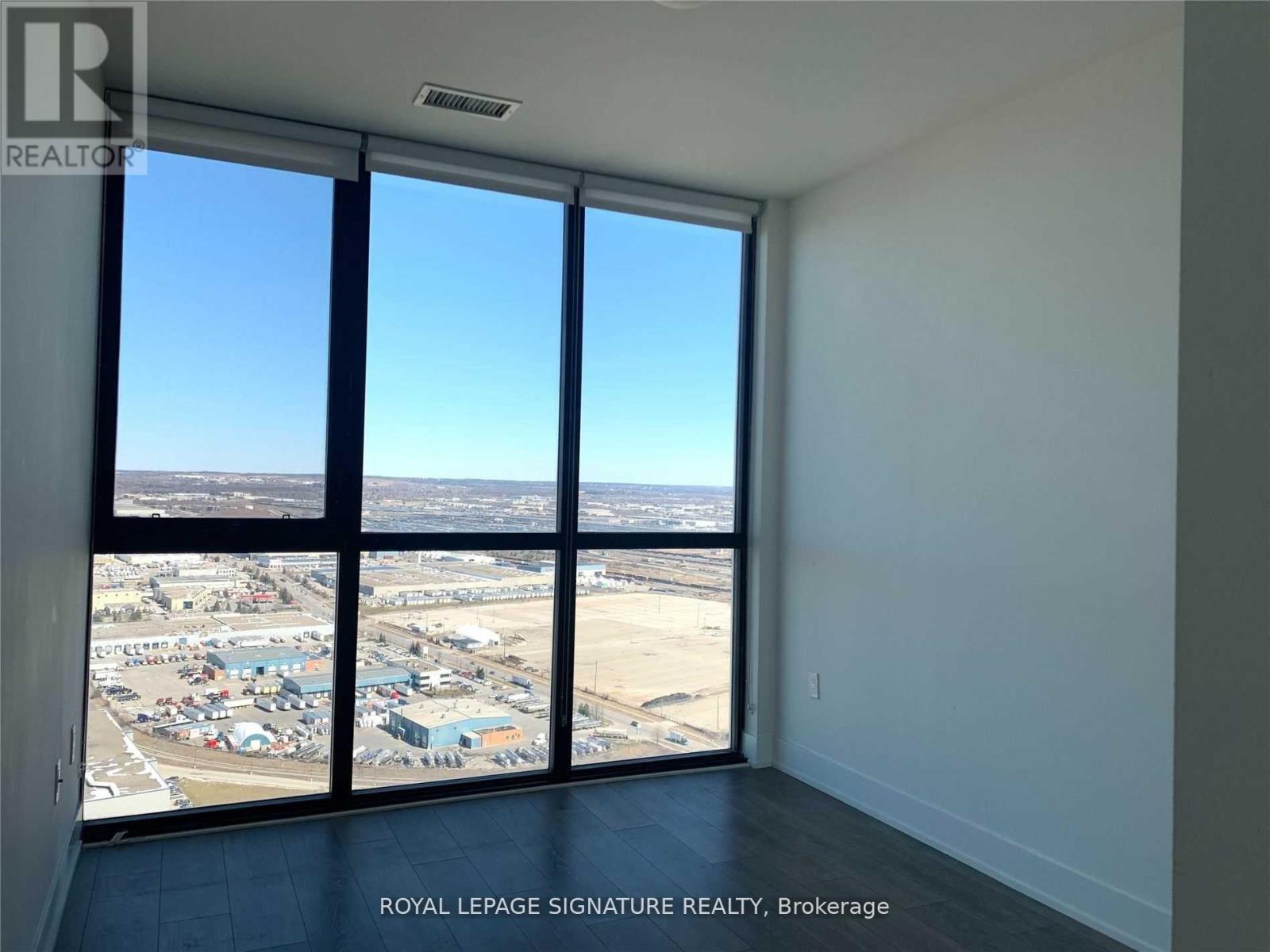 A room with a view of a parking lot from a window.