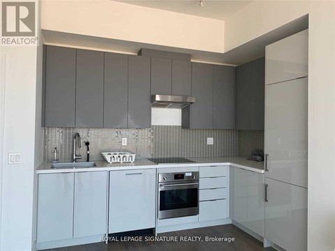 A kitchen with white cabinets and a black and white tiled backsplash.