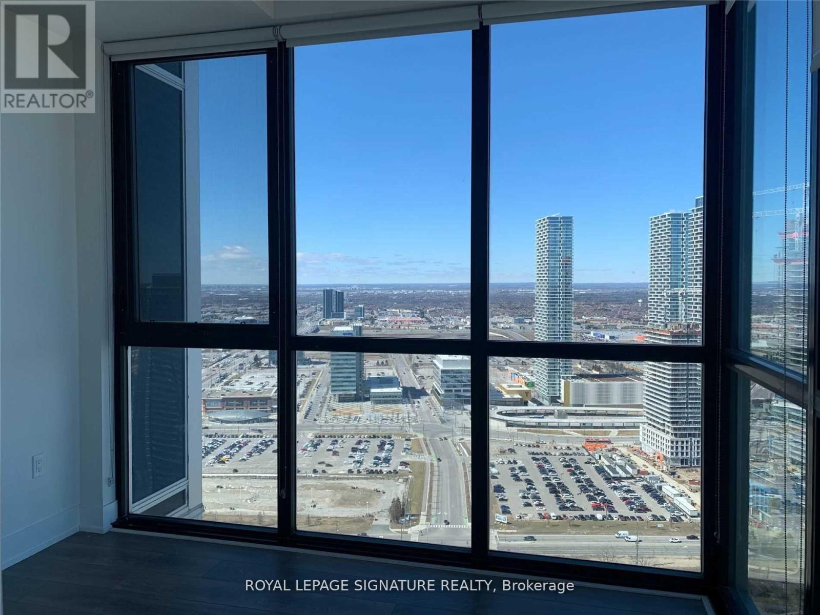 A view from a window looking out at a cityscape and a parking lot.