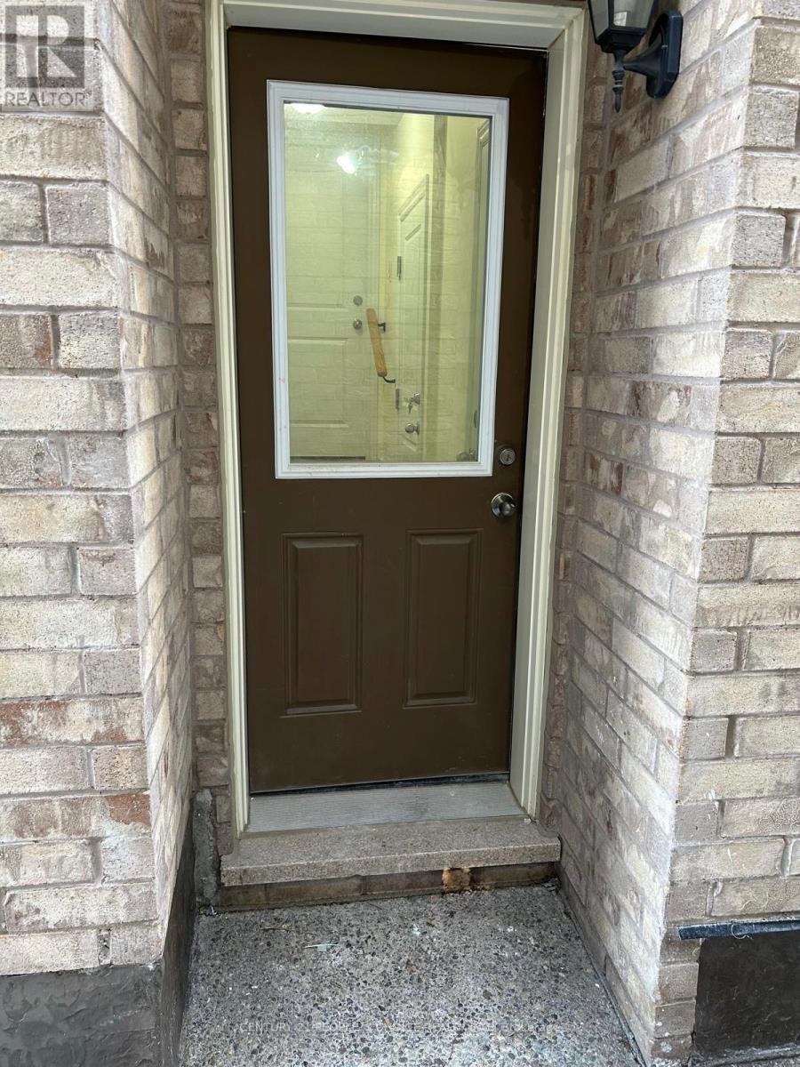 A brown door with a glass window is set in a brick wall.