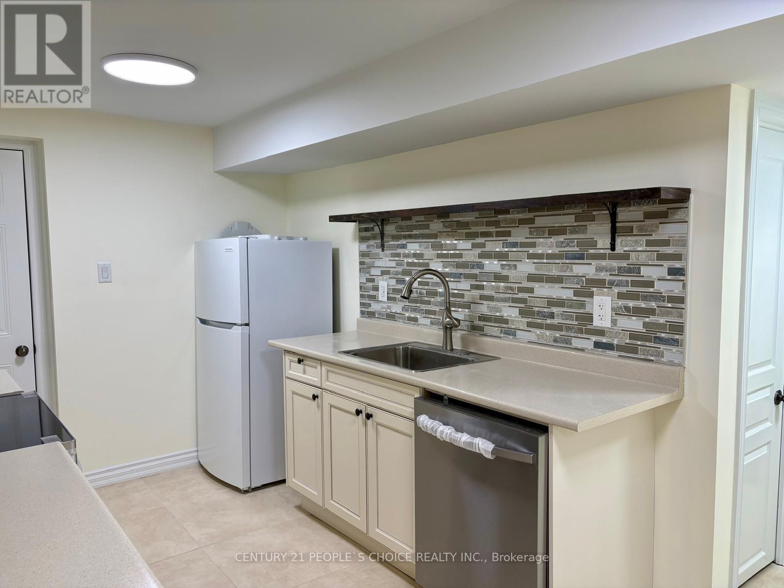 A kitchen with a refrigerator, sink, and cabinets.