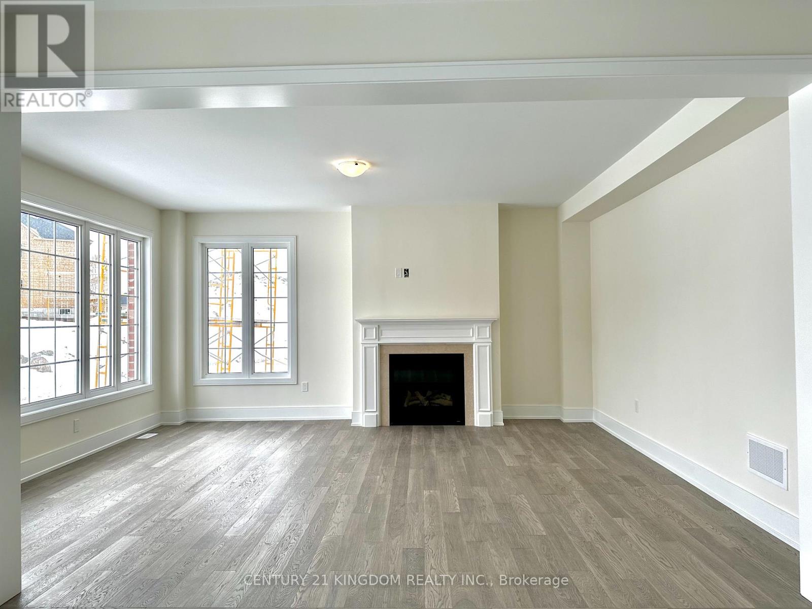 A large, empty room with a fireplace and wood flooring.