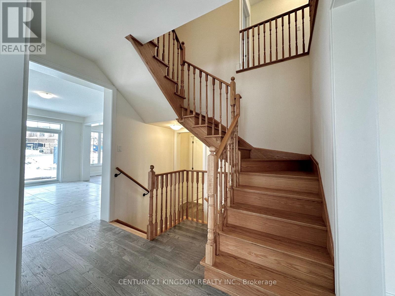 A wooden staircase with a metal railing in a white room.