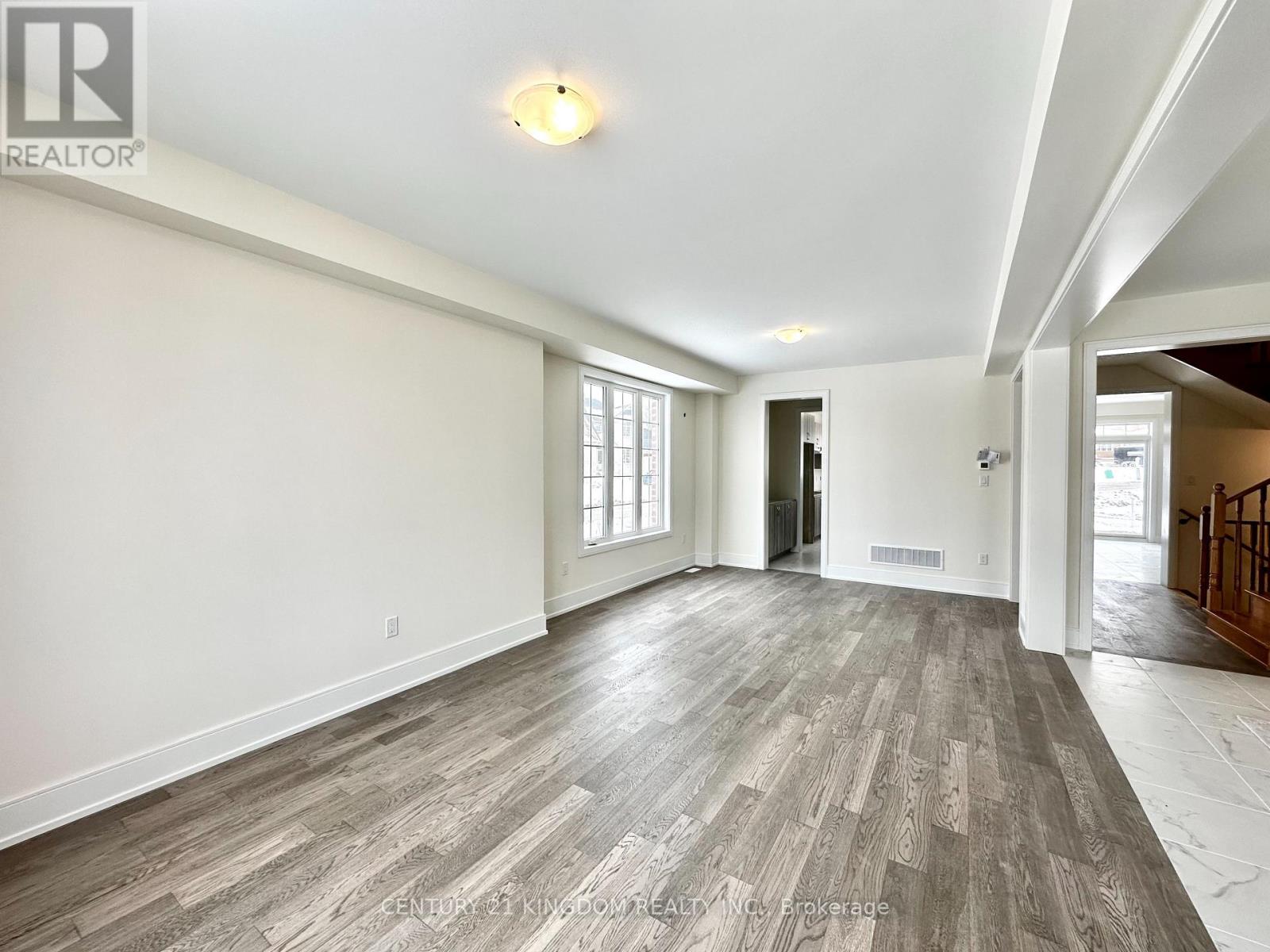 A spacious room with wooden flooring and white walls.