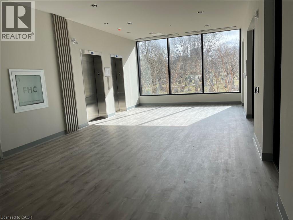 A spacious room with wooden flooring and large windows.
