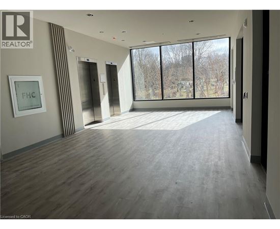 A spacious room with wooden flooring and large windows.