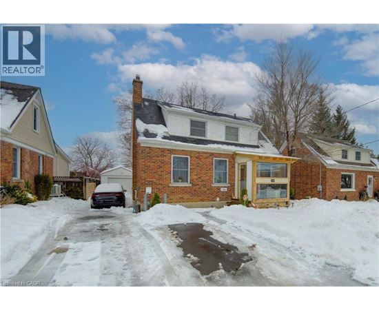 A house with a snow-covered driveway in front.