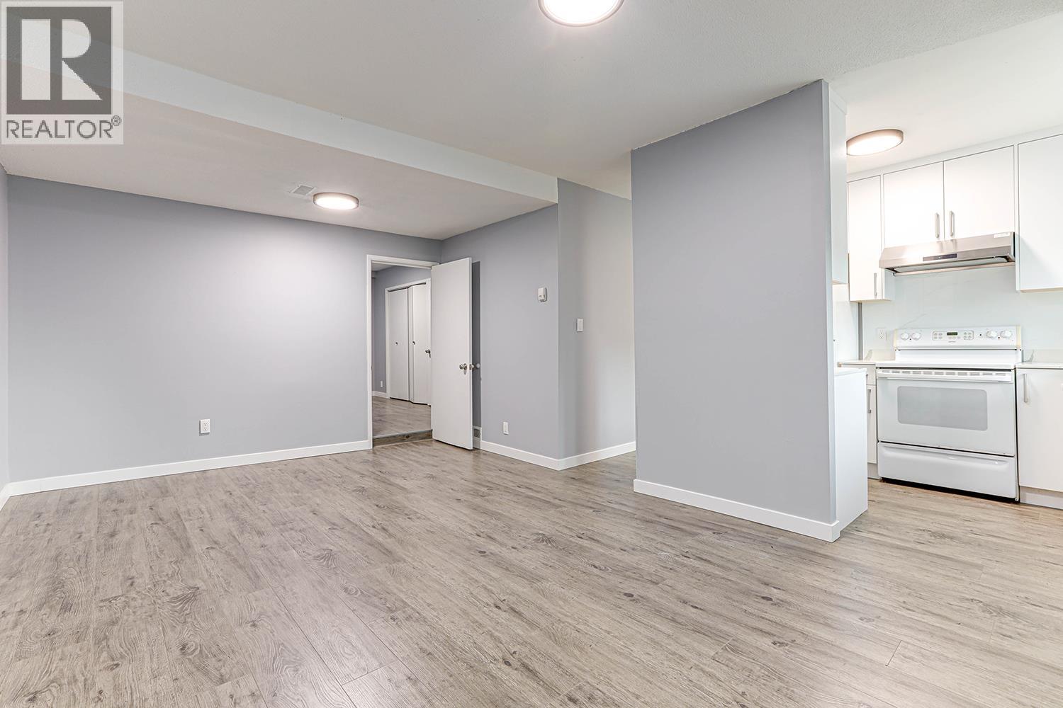 A spacious room with a kitchen area in the background.