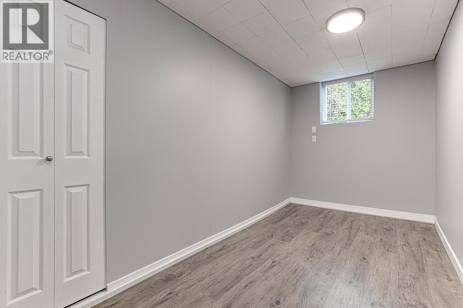A room with a white door and a window with a view of trees outside.