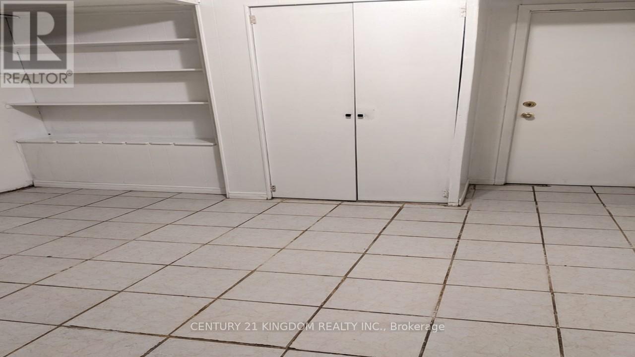 A white tiled room with a white door and a white shelf.