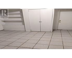 A white tiled room with a white door and a white shelf.